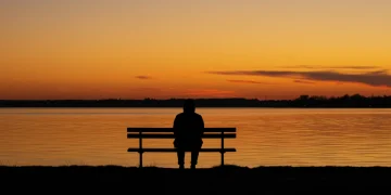 Coping with Grief & Loss: 4-Step Trauma Framework 2025 Person contemplating grief by a lake at sunset